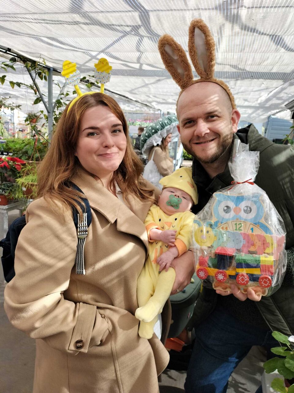 People smiling whilst holding baby and Easter baby toys