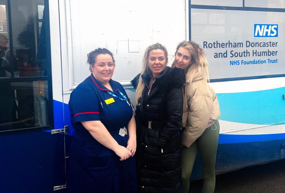 People smiling in front of health bus