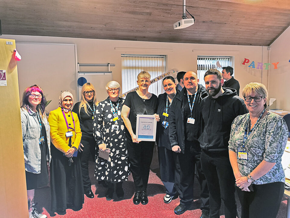 Person holding award surrounded by colleagues