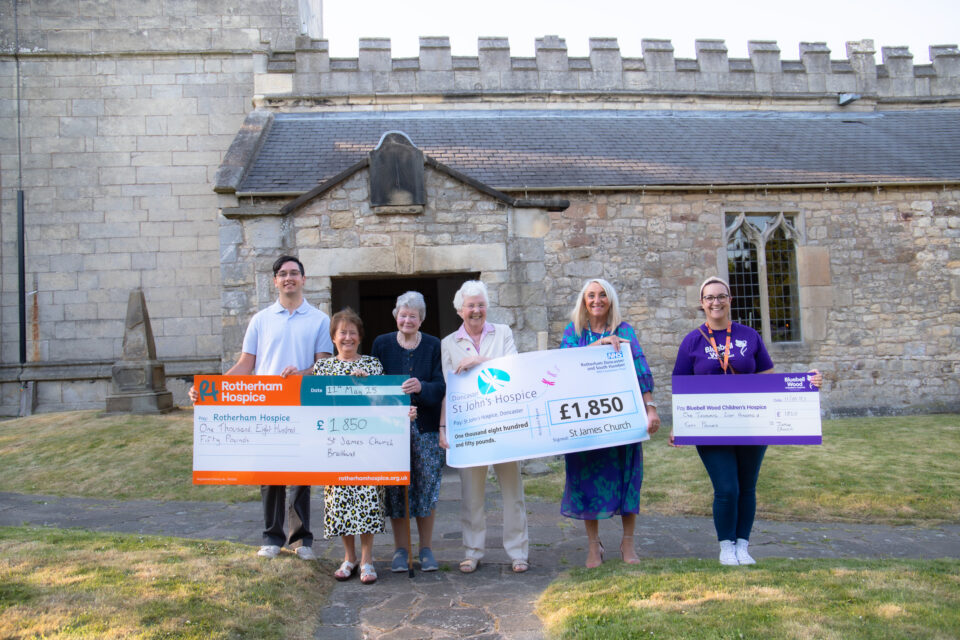 Six people holding up three cheques