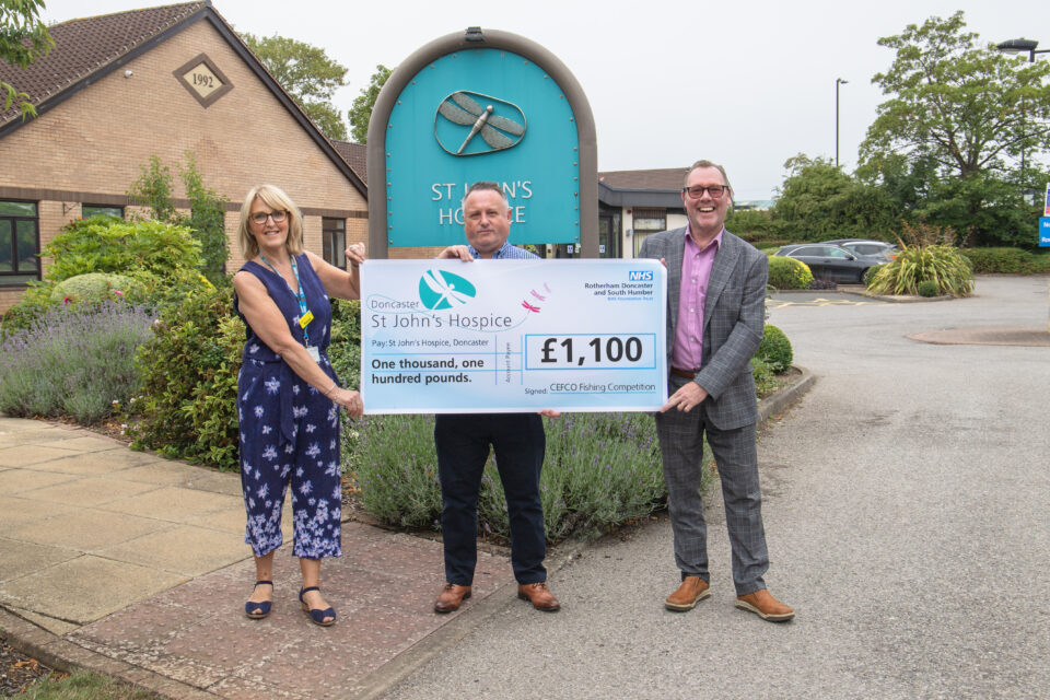 Three people holding a cheque for £1,100