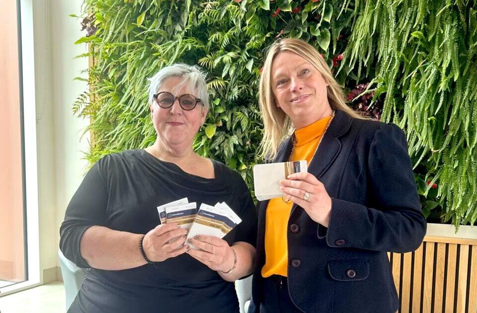 Two people holding up wellbeing leaflets
